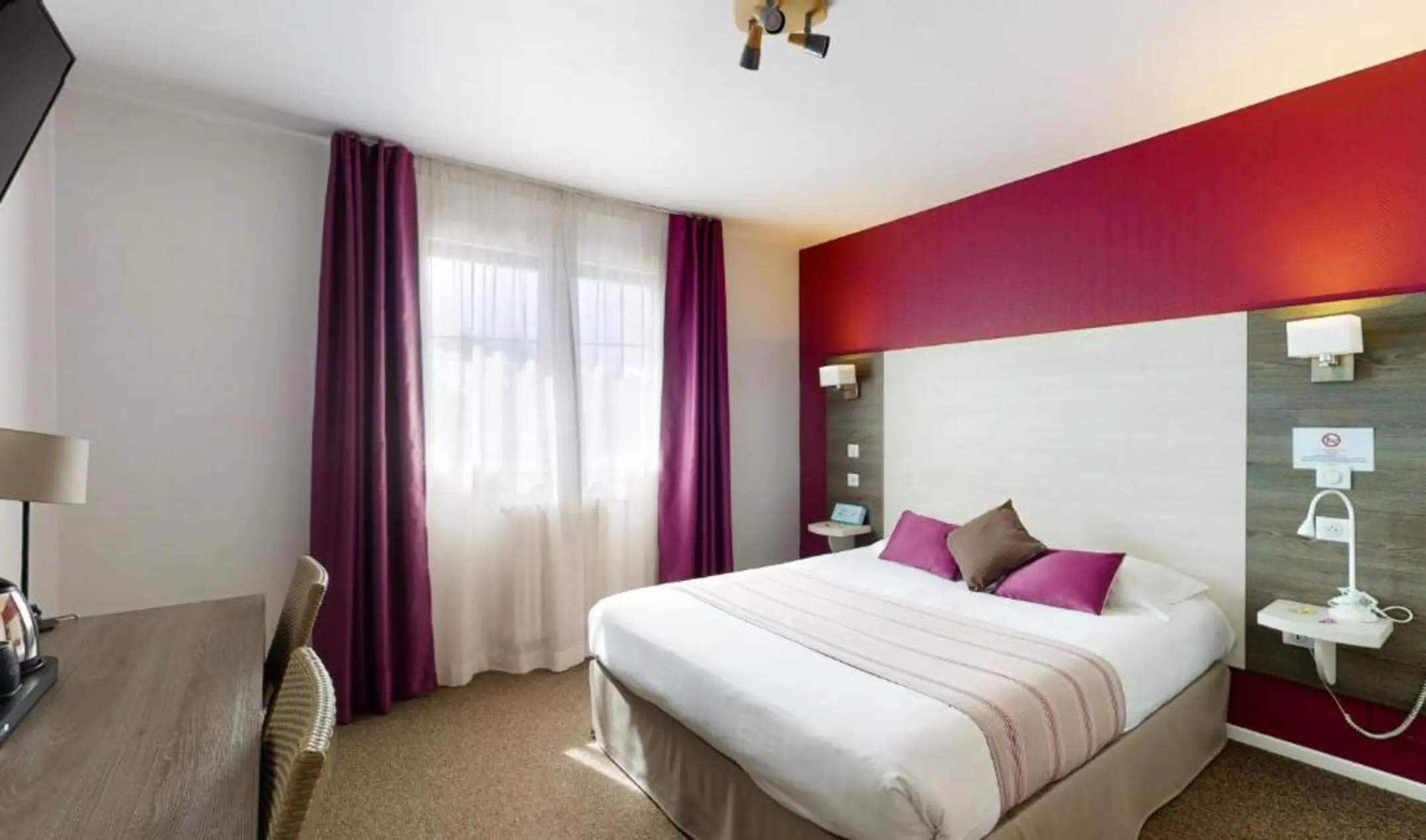 Grand lit double dans la chambre de l'hôtel Prado à Toulouse